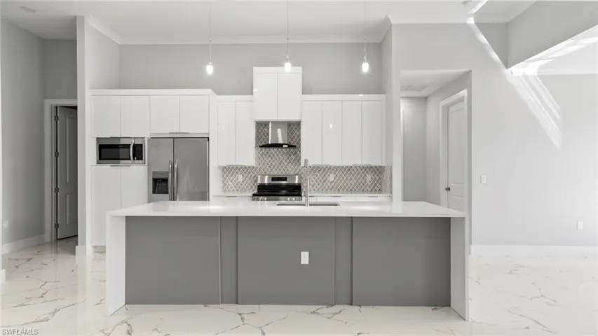 Kitchen featuring wall chimney range hood, modern cabinets, marble finish floor, and stainless steel appliances