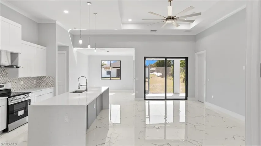 Kitchen featuring stainless steel electric range, open floor plan, a sink, modern cabinets, and wall chimney exhaust hood