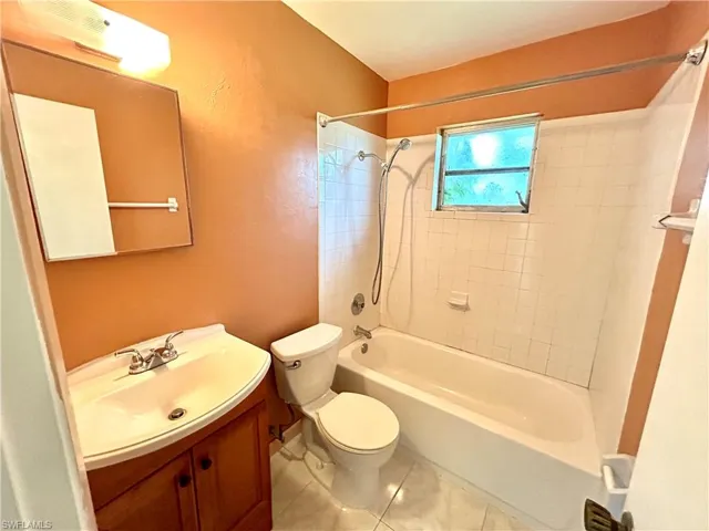 Full bathroom with tiled shower / bath combo, tile patterned floors, toilet, and vanity