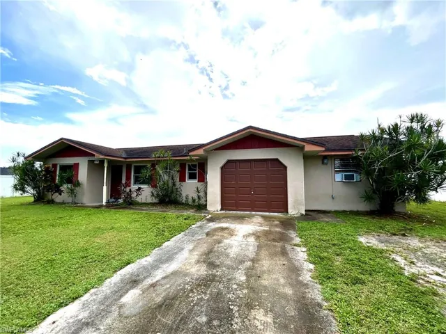 Ranch-style house featuring a garage and a front lawn