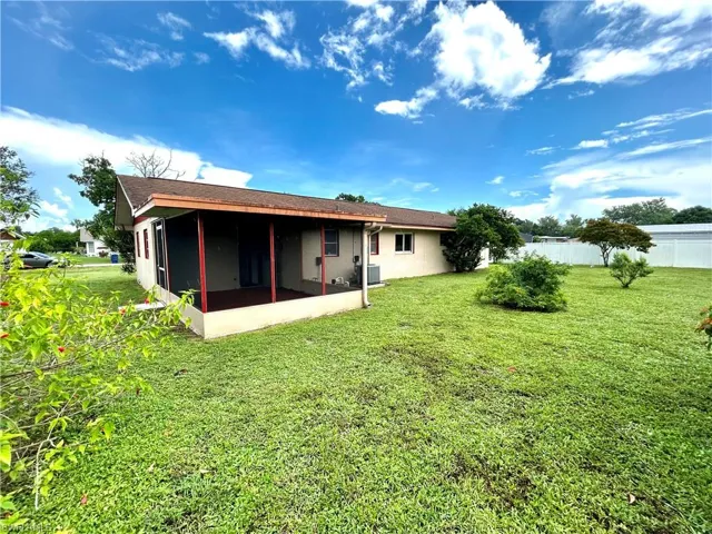 Rear view of property with a lawn, central AC, and a sunroom
