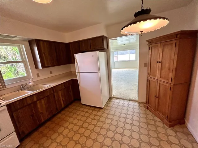 Kitchen with sink, light tile patterned flooring, and white refrigerator