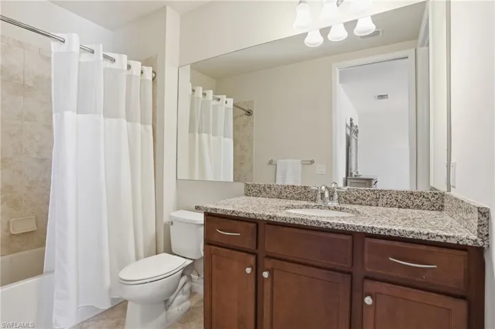 Full bath featuring shower / tub combo with curtain, vanity, and light tile patterned floors