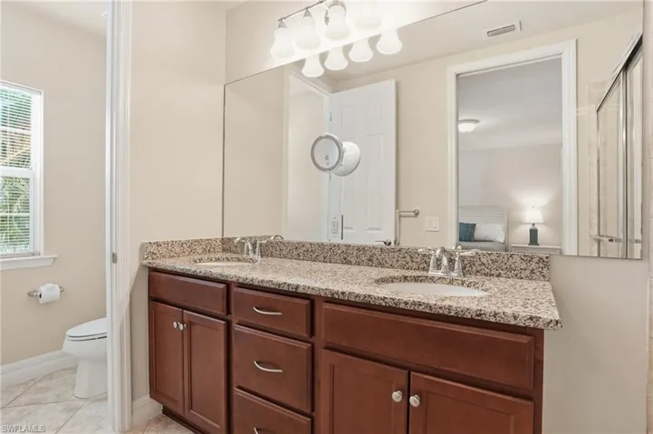 Bathroom with double vanity, connected bathroom, and light tile patterned floors
