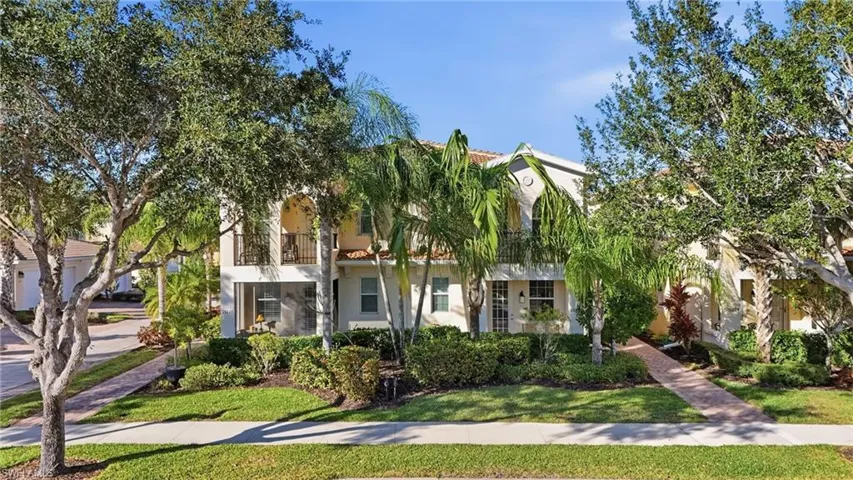 View of front of house featuring stucco siding, a front lawn, and a balcony