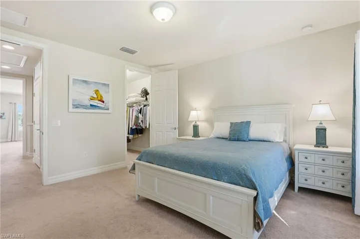 Bedroom with light colored carpet and a walk in closet