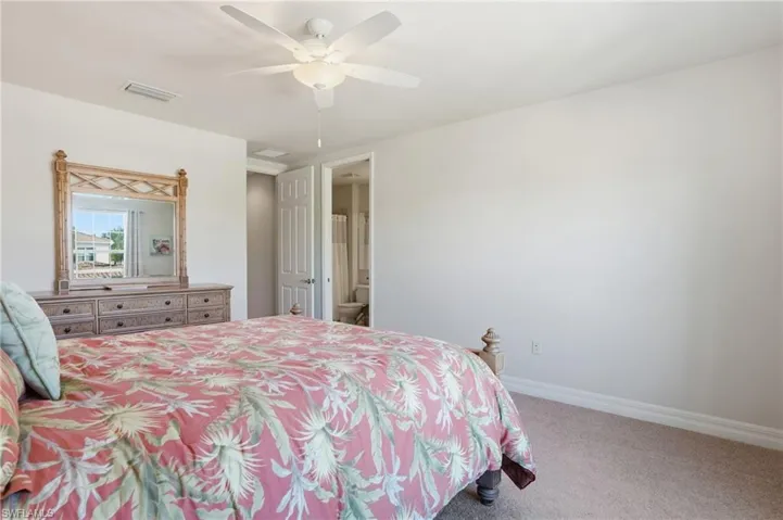 Bedroom with carpet flooring, a ceiling fan, and ensuite bath