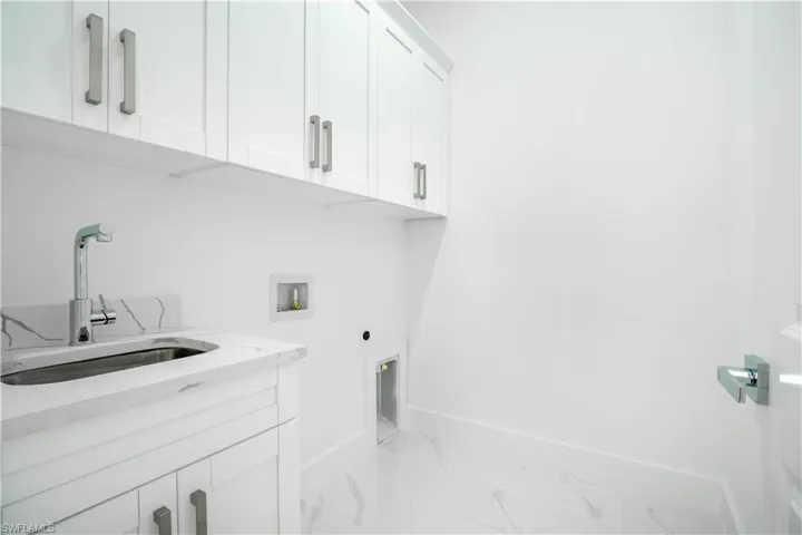 Laundry room featuring hookup for a washing machine, sink, cabinets, light tile patterned floors, and hookup for an electric dryer