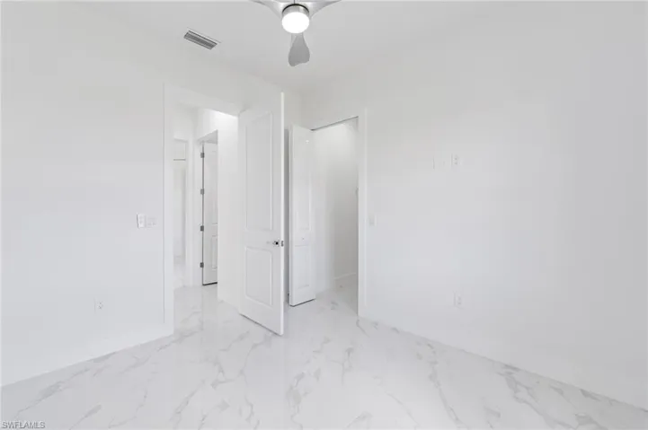Tiled spare room featuring ceiling fan