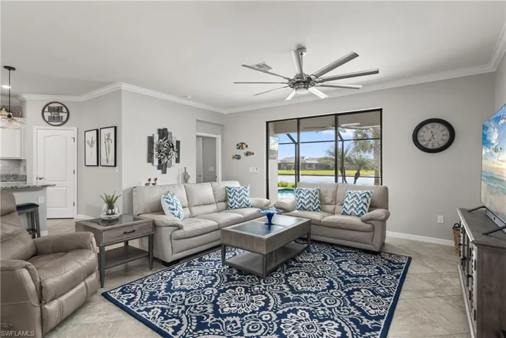 The great room features tile flooring, extra large ceiling fan, slider to outdoor living space and pool area.