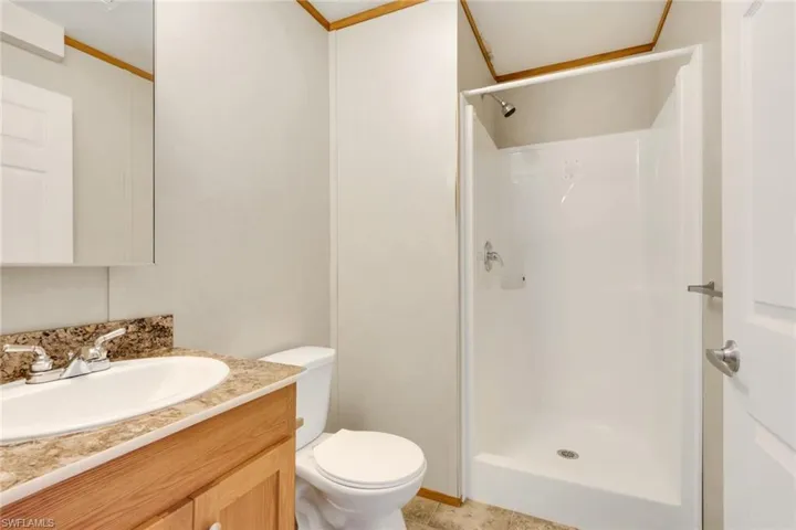 Bathroom with a shower stall, vanity, and ornamental molding