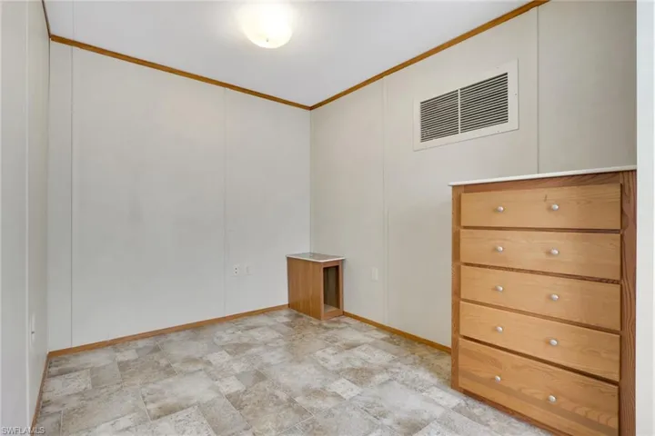 Empty room featuring crown molding, stone finish floors, and a decorative wall