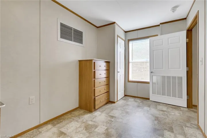 Unfurnished bedroom with crown molding and baseboards