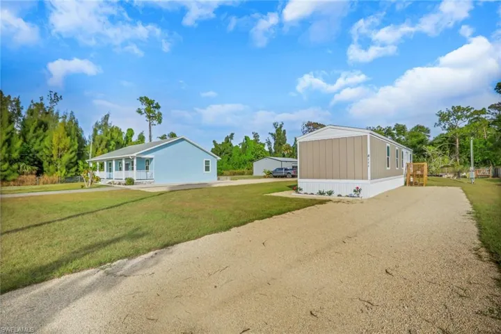 View of property exterior featuring a lawn and driveway