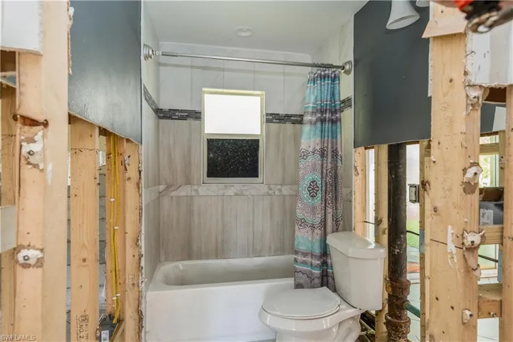 Bathroom with toilet and shower / bathtub combination with curtain