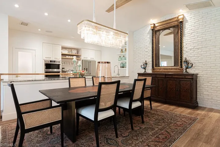 Sideboard with textured white brick accent wall and crystal chandelier