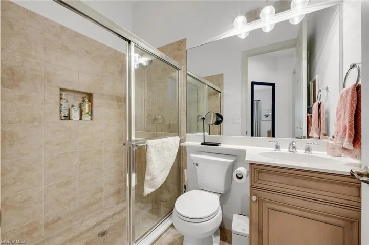 Bathroom featuring vanity, toilet, and a shower with door
