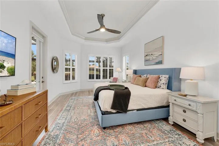 Bedroom with ceiling fan, crown molding, light hardwood / wood-style flooring, and a tray ceiling