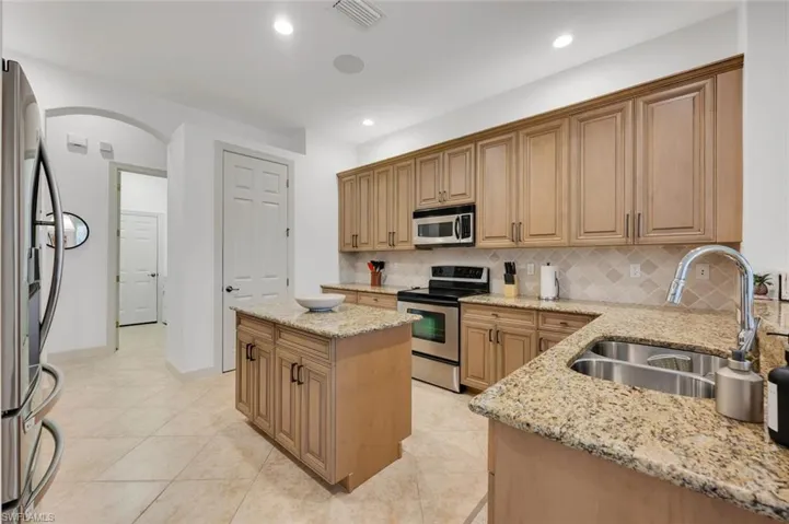 Kitchen featuring light stone counters, sink, appliances with stainless steel finishes, and a kitchen island