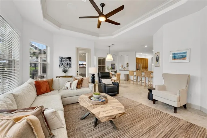 Living room with ceiling fan, a tray ceiling, and crown molding