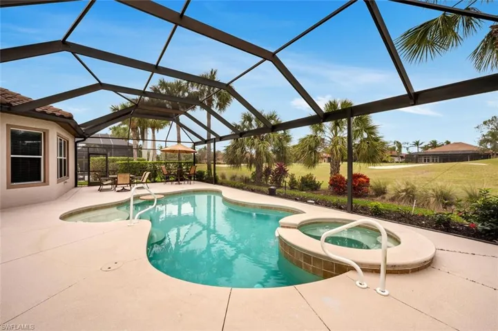 View of swimming pool with a lanai, a patio area, and an in ground hot tub