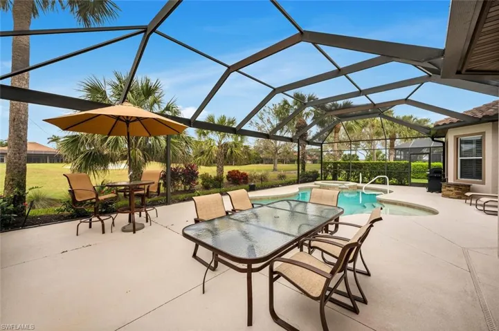View of patio / terrace with grilling area, a swimming pool with hot tub, and glass enclosure