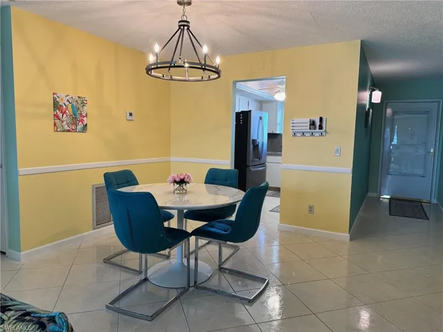 Dining room with light tile patterned flooring, a textured ceiling, and a chandelier