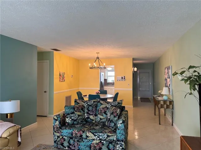 Living room featuring a chandelier, a textured ceiling, and light tile patterned floors