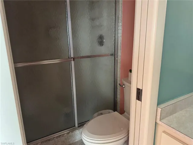 Bathroom featuring toilet, walk in shower, and vanity