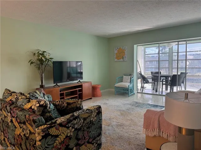 Living room with a wealth of natural light, tile patterned floors, and a textured ceiling