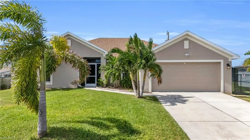 View of front of house with driveway, an attached garage, fence, a front yard, and stucco siding