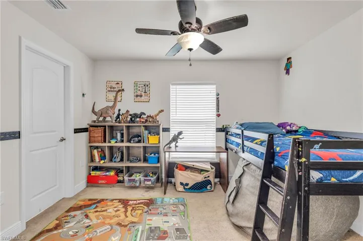 Carpeted bedroom featuring baseboards, a ceiling fan, and visible vents