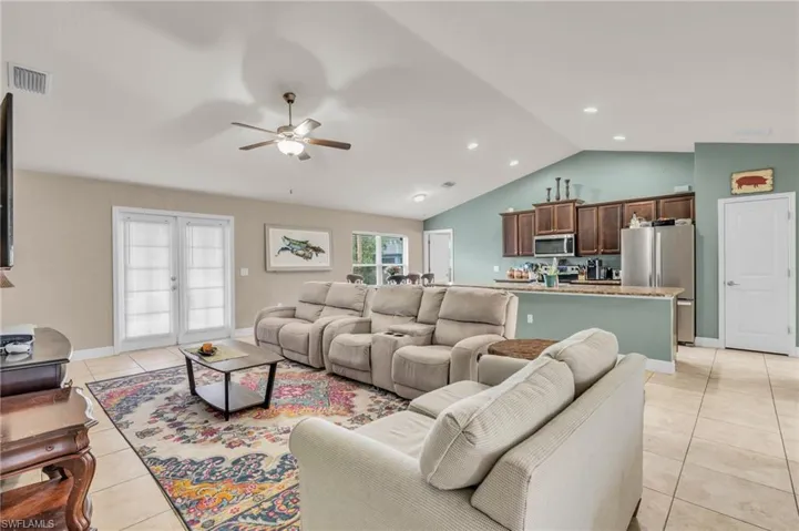 Living area with vaulted ceiling, baseboards, visible vents, ceiling fan, and light tile patterned floors