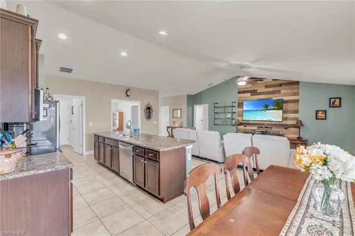 Kitchen featuring stainless steel appliances, a sink, light tile patterned flooring, vaulted ceiling, and a ceiling fan