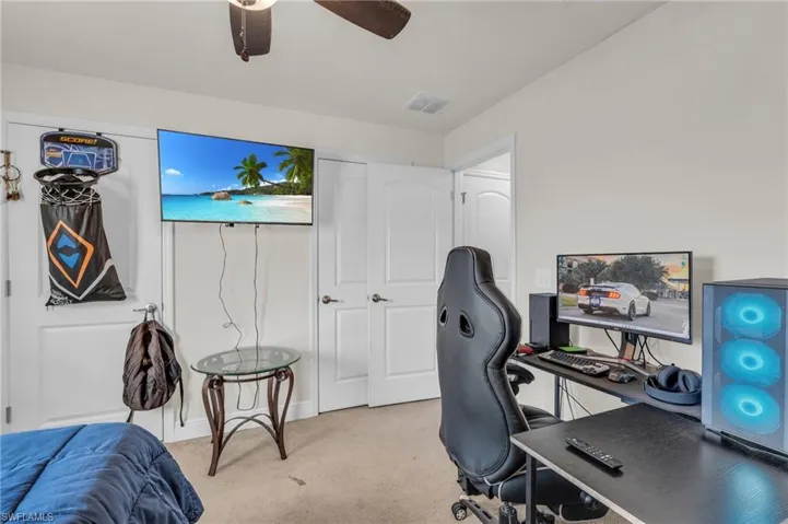 Office space with baseboards, a ceiling fan, visible vents, and light colored carpet