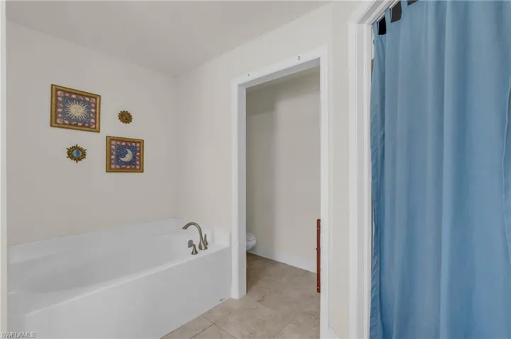 Full bath featuring a bath, toilet, tile patterned flooring, and baseboards