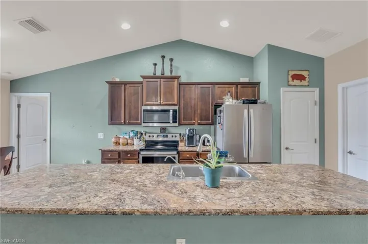 Kitchen featuring lofted ceiling, stainless steel appliances, visible vents, and a sink