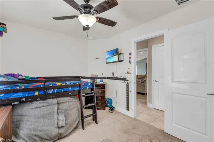 Tiled bedroom with ceiling fan, carpet floors, visible vents, and baseboards