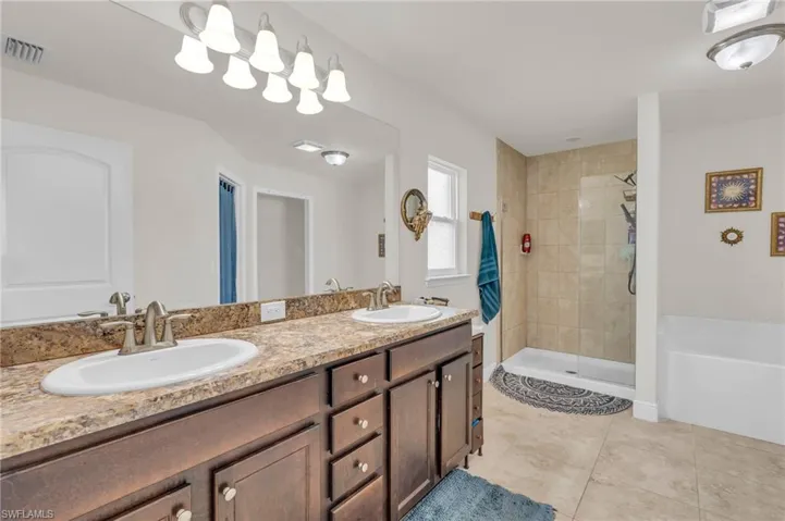 Bathroom with tile patterned floors, visible vents, a sink, and a shower stall