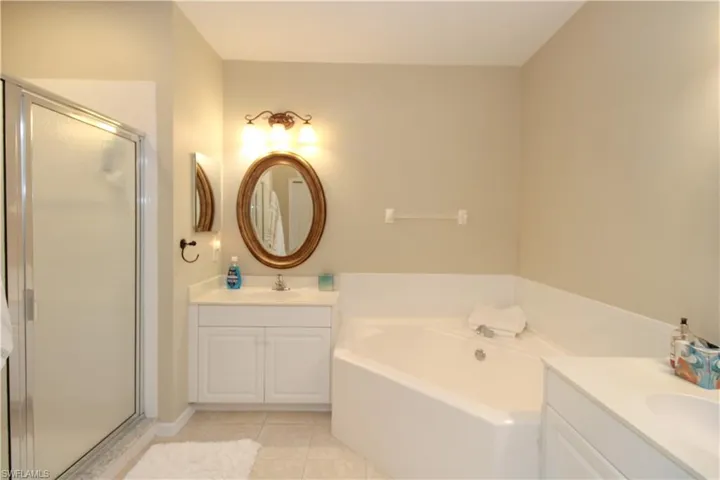 Bathroom featuring tile patterned floors, vanity, and separate shower and tub