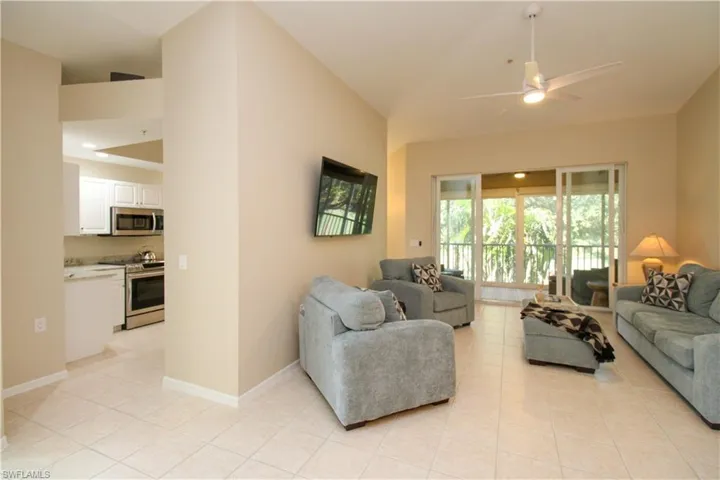 Tiled living room featuring vaulted ceiling and ceiling fan