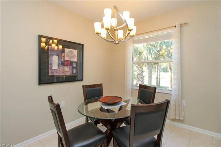 Dining area with light tile patterned floors and an inviting chandelier