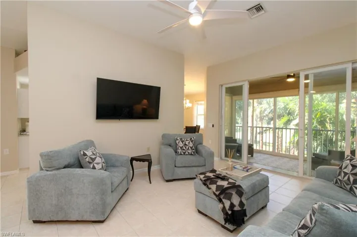 Living room featuring light tile patterned flooring and ceiling fan with notable chandelier