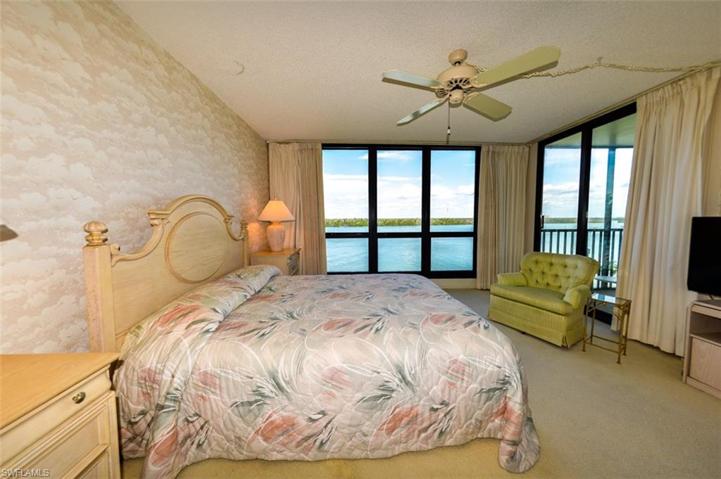 OWNER'S SUITE WITH NEARLY FLOOR-TO-CEILING IMPACT RESISTANT WINDOWS SHOWCASING ESTERO BAY.  ENTRANCE TO LANAI IS THROUGH SLIDING DOORS AT RIGHT.