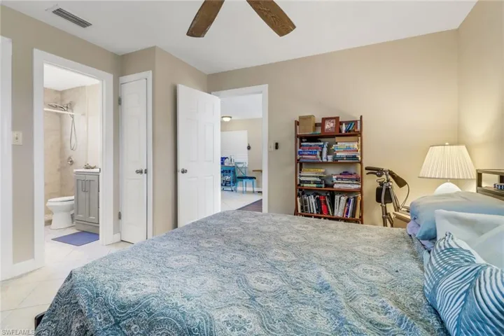 Bedroom featuring light tile patterned floors, ensuite bath, and ceiling fan