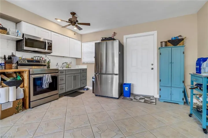 Kitchen featuring appliances with stainless steel finishes, ceiling fan, white cabinets, open shelves, and backsplash