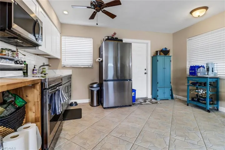 Kitchen with appliances with stainless steel finishes, a ceiling fan, white cabinetry, and wood counters