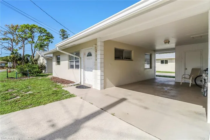 Entrance to property with an attached carport, stucco siding, and a yard