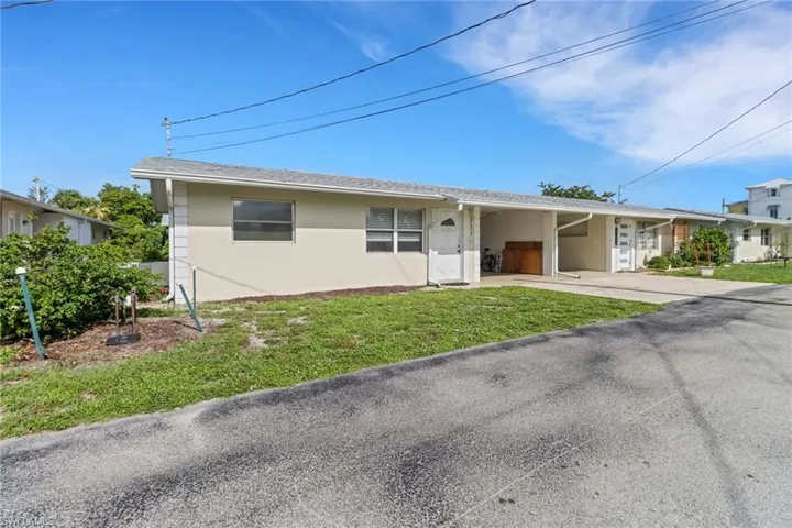Single story home with an attached carport, stucco siding, concrete driveway, a front yard, and roof with shingles