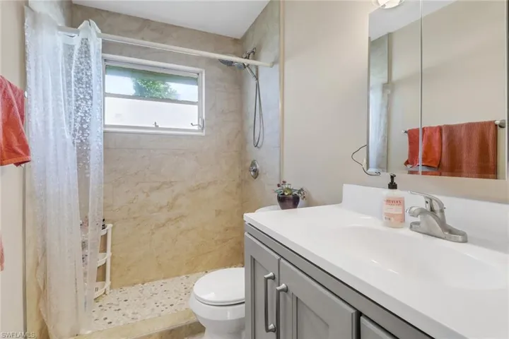 Full bath with tiled shower and vanity